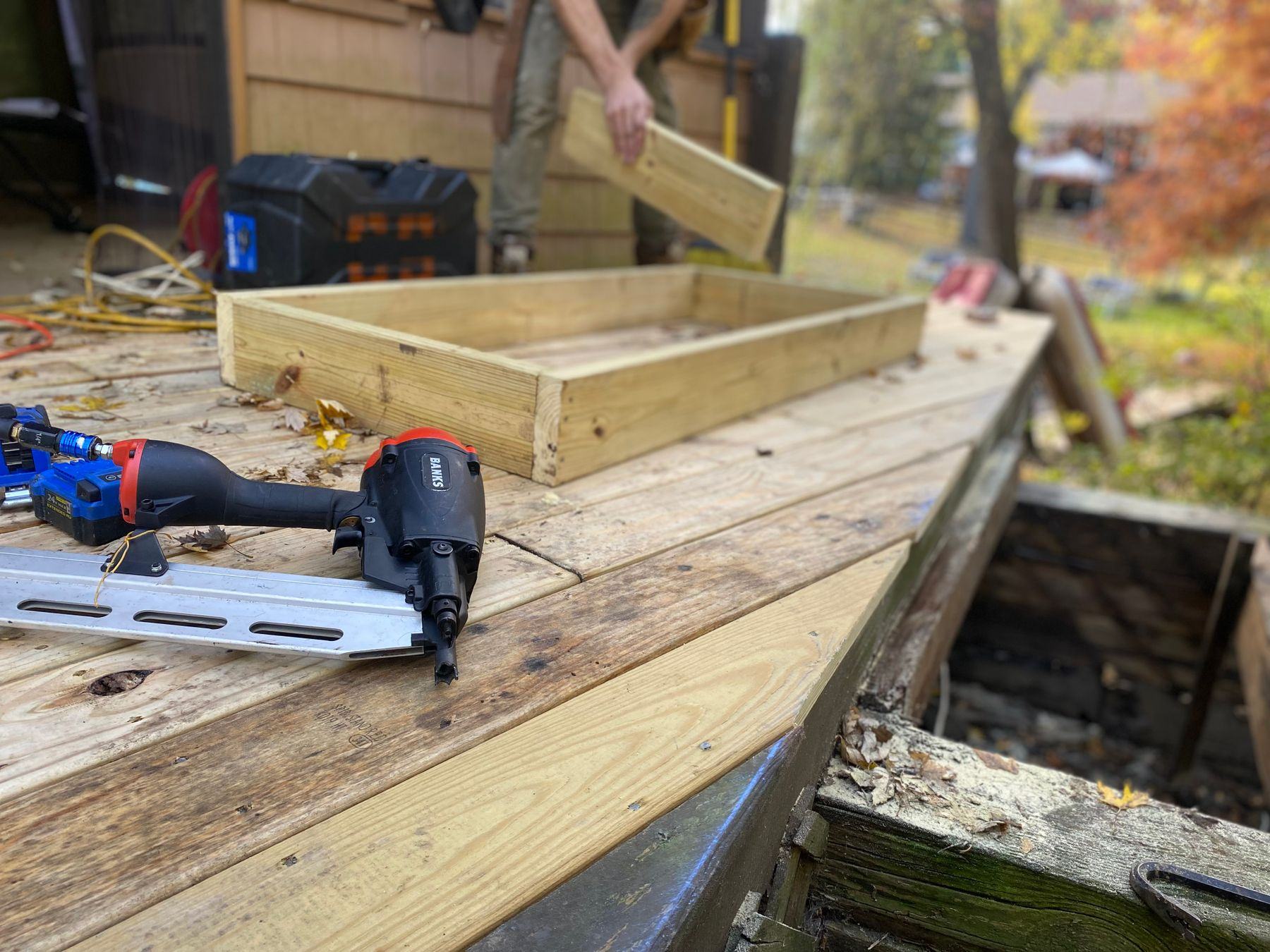 A nail gun resting on new deck boards and framing during construction